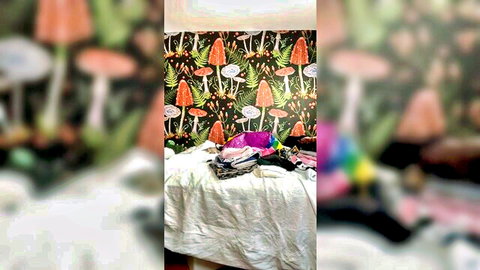 Colorful panties bras and lingerie piled on bed against trippy mushroom wallpaper