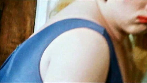 Blonde woman with red lips and blue sleeveless top in teasing closeup pose