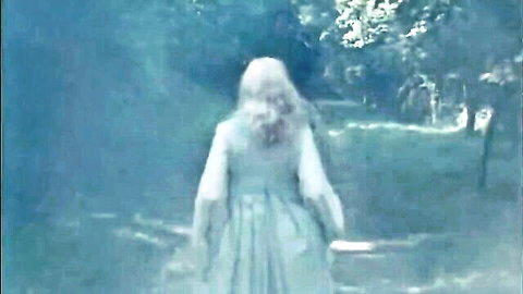 Mysterious blonde in white dress walking in eerie forest, vintage tease with Rocco Siffredi vibes