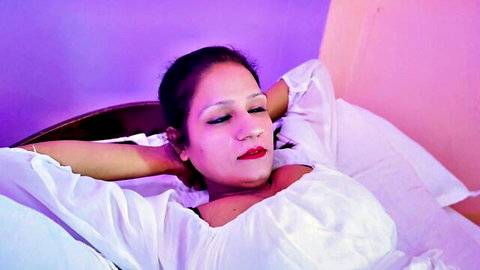 Relaxed Indian domina in white off-shoulder dress, big cleavage, ready to dominate submissive guy