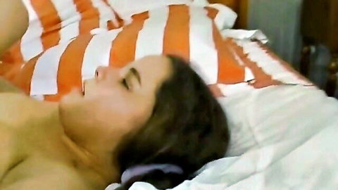 Topless brunette babe with big tits lies on bed eyes closed mouth open