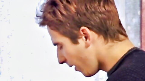 Young man with short brown hair in profile, looking down intently in intimate scene