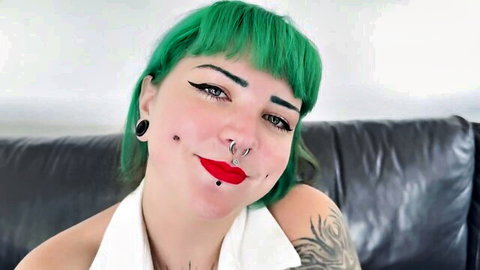 Green-haired pierced babe with septum ring smiling seductively showing cleavage in white top