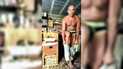 Bald muscular man pulling down underwear for solo anal tool play