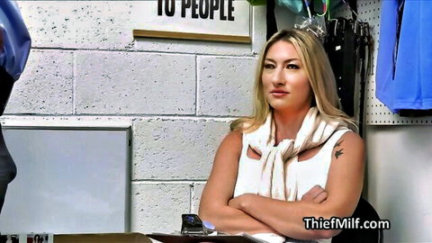 Blonde MILF in office, arms crossed, teasing before BBW strap-on action