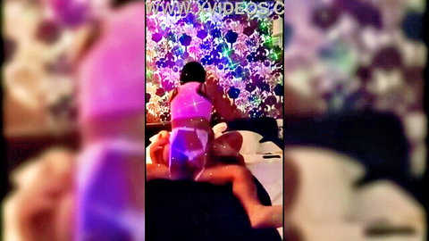 Trans woman in pink lingerie sitting seductively in vibrant lights