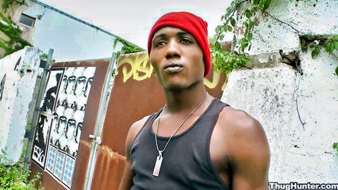 Muscular black thug in red beanie and tank top posing outdoors