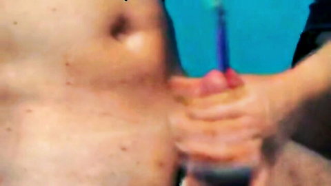 Man's close-up urethral sounding with blue rod insertion, explicit male fetish
