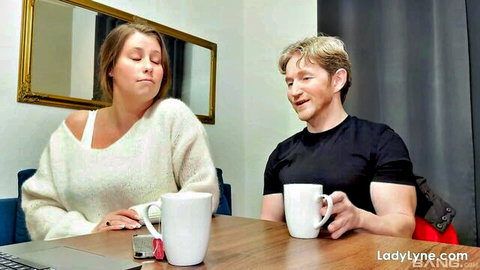 Curvy brunette MILF in off-shoulder sweater sips coffee with muscular ginger stud at table