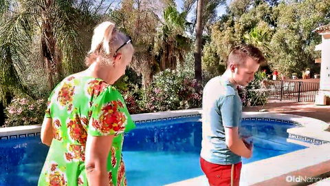 Mature blonde in floral dress teases young boyfriend poolside