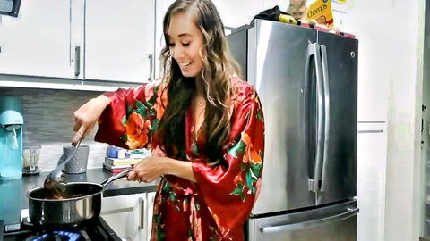 Brunette in silky red floral robe stirring pan seductively in kitchen