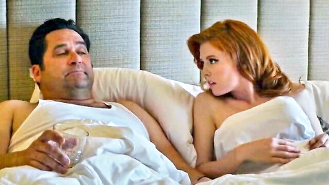 Surprised redhead with medium tits lying nude beside shirtless Latino hunk holding drink in bed