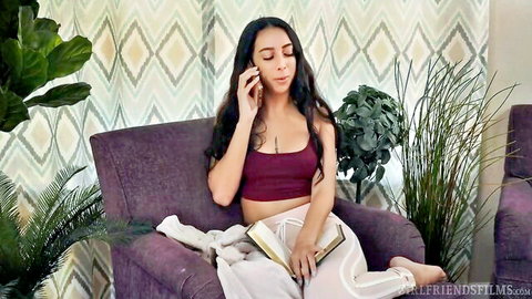 Chloe Amour lounging in maroon tank top and white pants on phone call
