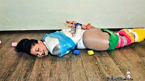 Bound Asian woman in tight bodysuit with colorful wraps, solo bondage scene