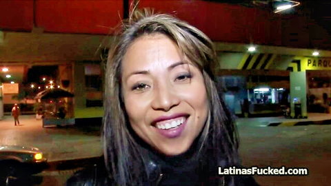 Smiling Latina woman in leather top, night parking lot pickup tease