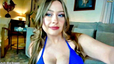Busty blonde temptress in blue halter top teasing with cleavage