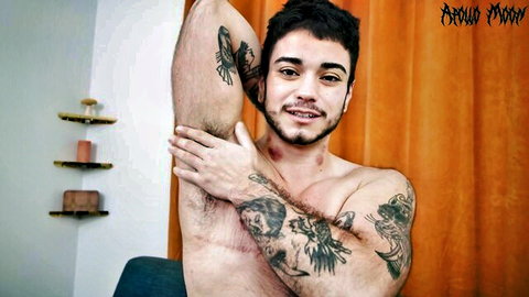 Tattooed muscular young guy smiles shirtless flexing armpit and hairy body