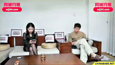 Sexy East Asian wife in sheer black lingerie and stockings teases husband on couch
