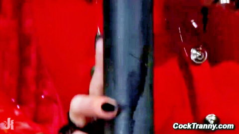Tanned hand with long black nails gripping thick metal pole in red room on CockTranny