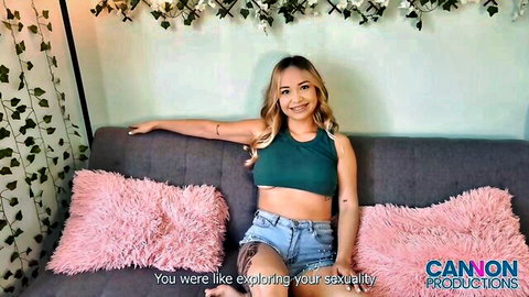 Isabella smiling in green crop top and denim shorts, exploring her sexuality solo