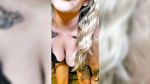 Smiling blonde with tattoos in black lace bra showing deep cleavage