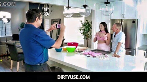 Brunette babe in open pink apron flashes big tits posing for older man's phone pic in kitchen