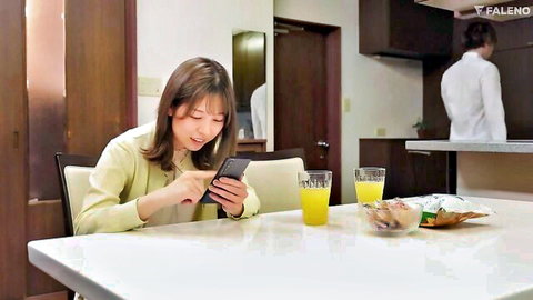 Japanese woman in yellow cardigan browsing phone at table, another in background