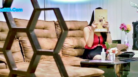 Indian MILF in red top and skirt hides face with book, teasing viewer
