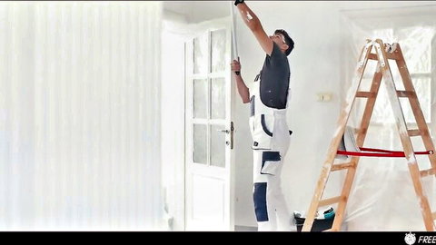 Kristof Cale in white overalls painting high on ladder, renovation scene