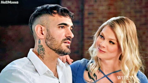 Tattooed bearded man embraces smiling blonde MILF wife intimately