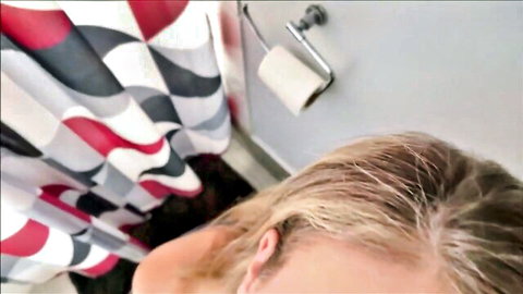Blonde Gigi Dior leaning in bathroom, teasing oral hint with Alex Adams