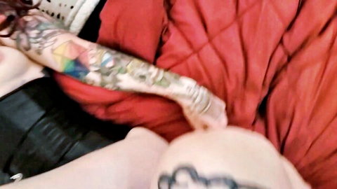 Tattooed emo girl with rainbow arm tats pushes bald man's head to her crotch on red bed