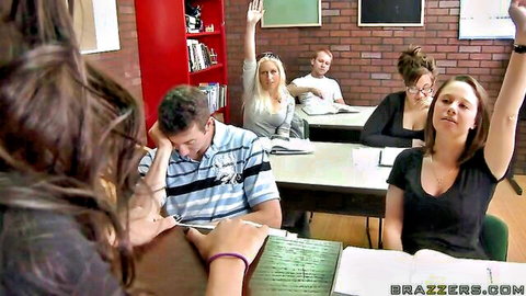 Blonde teacher instructs class of students raising hands in classroom