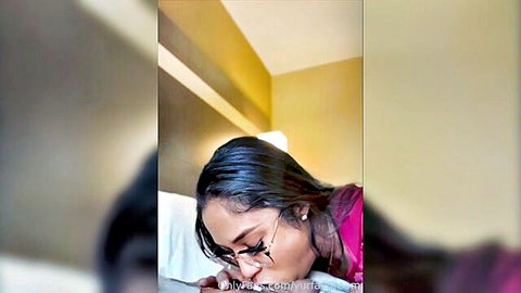 Korean woman with glasses lying face down on bed in pink top