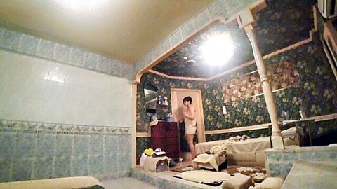 Slim Asian woman in light slip standing in doorway, amateur JAV scene