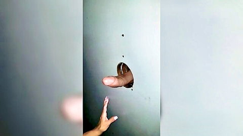 Woman's hand reaching for hard cock through gloryhole in wall
