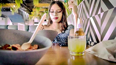 POV Asian woman with glasses in polka dot dress eating soup and sipping beer