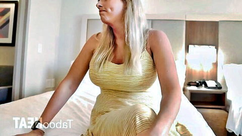 Busty blonde stepmom lounging in yellow dress on vacation bed