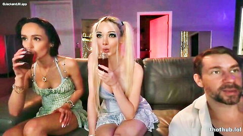 Blonde girl with pigtails holding bottle excitedly on couch with friends sipping drinks
