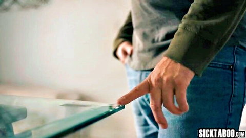 Man in green shirt and jeans pointing finger at glass table edge