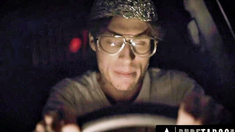 Conspiracy theorist in foil hat and glasses smirks in dark car, teasing alien anal probe