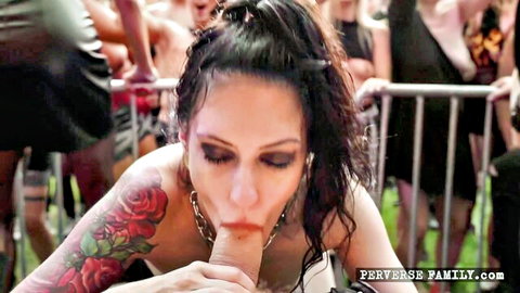 Tattooed brunette giving blowjob at perverse rock fest outdoor event