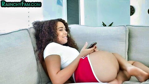 Smiling curly-haired ebony beauty in white top and red shorts, big ass visible