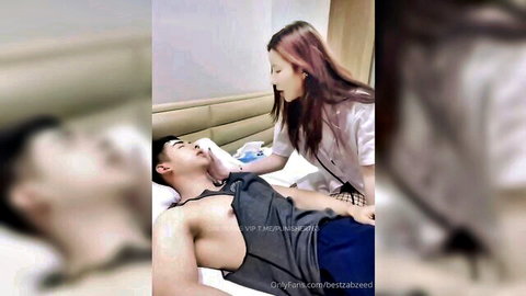 Redhead nurse in white blouse leans over shirtless man on bed, hand on his chin teasing intimately