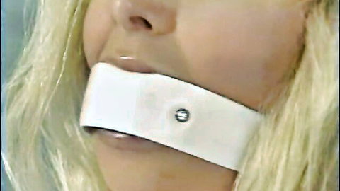 Blonde submissive woman with white tape gag over mouth in BDSM bondage closeup