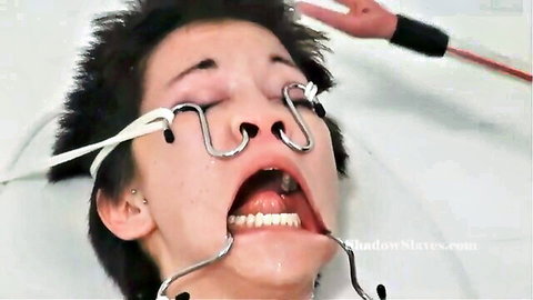 Asian woman enduring nose and mouth hook torture in BDSM scene