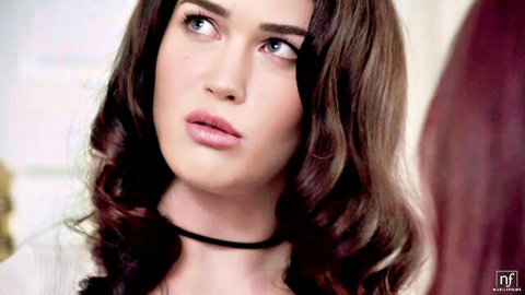 Seductive brunette with long wavy hair and black choker gazes intensely with plump lips parted