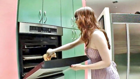 Lexi Kartel bends over in striped dress pulling tray from oven