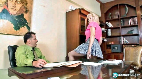 Blonde Marina bent over desk in pink top and plaid skirt for John Holmes