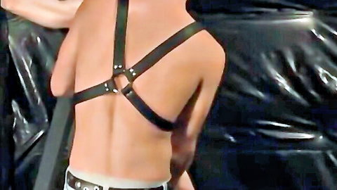 Brendon Meyers in leather harness, back view of Axel being fondled in gay BDSM